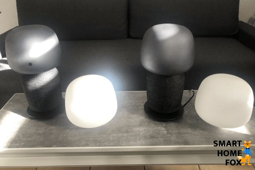 Man sieht die Symfonisk Tischleuchte und den Symfonisk Regal-Lautsprecher nebeneinander stehen. 